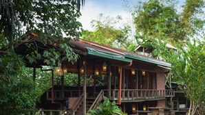 A rustic wooden building with a balcony, surrounded by lush greenery. - Paganakan Dii Tropical Retreat (Sandakan)