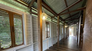A corridor with wooden floors and slatted windows, leading to an open area. - Paganakan Dii Tropical Retreat (Sandakan)