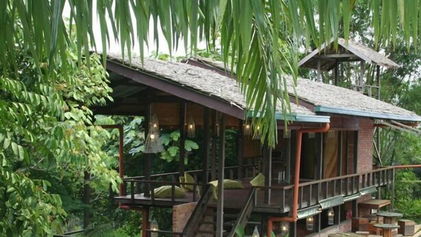 A wooden cabin with a balcony, surrounded by lush greenery. - Paganakan Dii Tropical Retreat (Sandakan)
