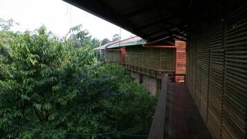 A covered outdoor area with a wooden deck, surrounded by dense foliage.