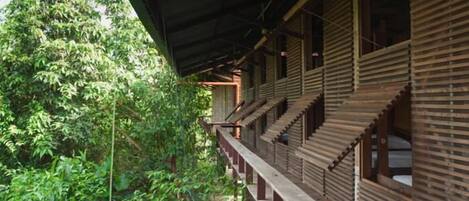 Un edificio de madera tradicional con un corredor cubierto y varias habitaciones.