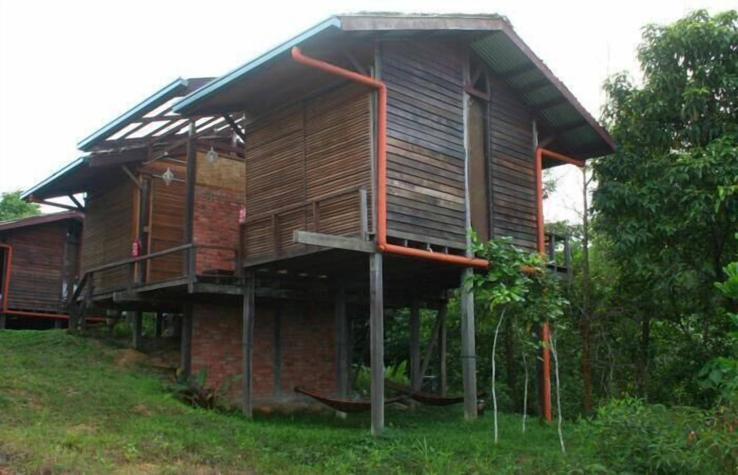 Una casa de madera de dos pisos con techo inclinado y base de ladrillo.