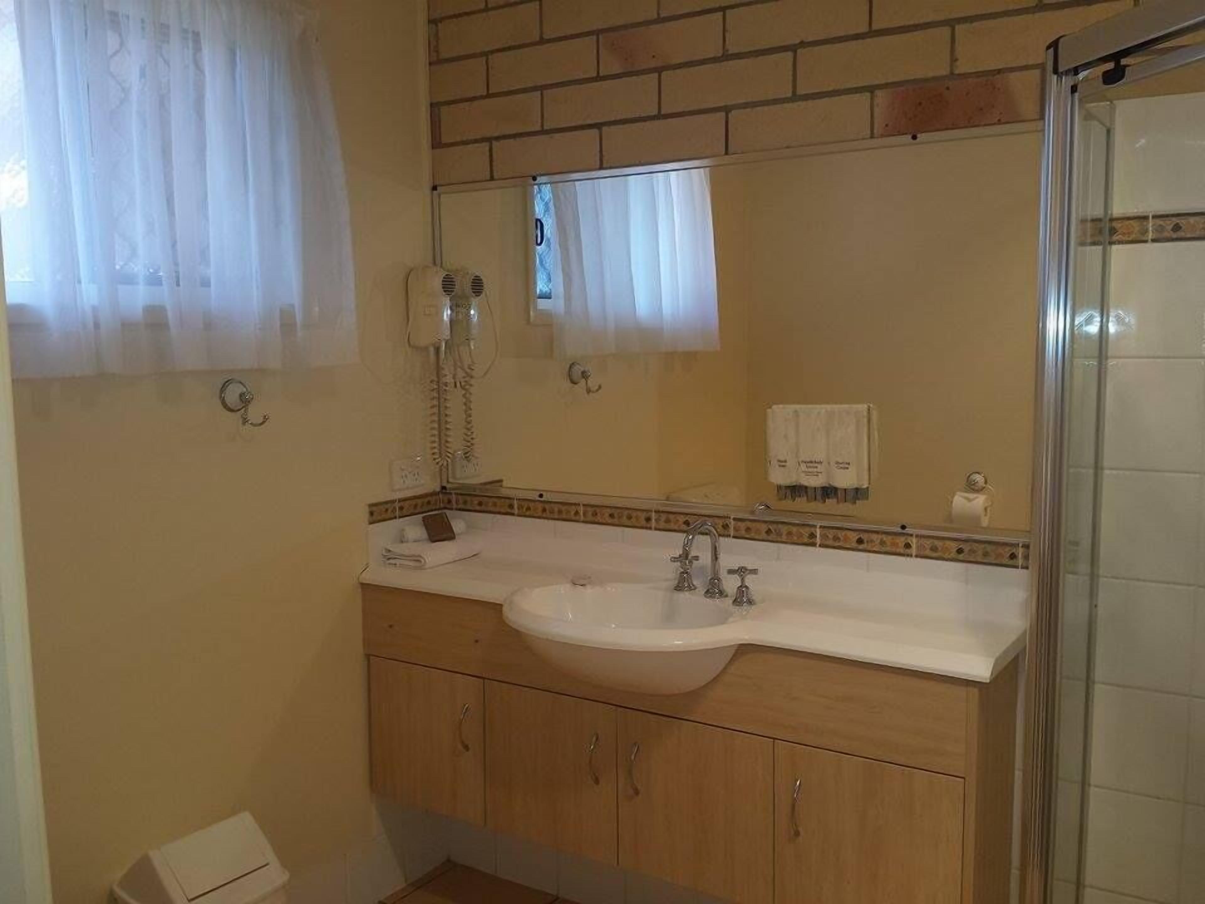 Un baño con lavamanos, espejo y perchero para toallas.