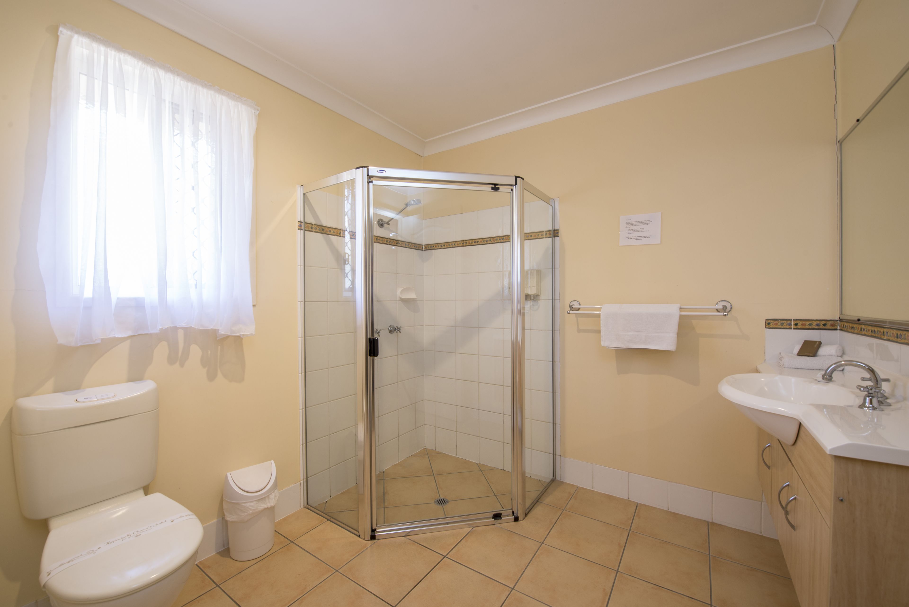 A bathroom with a glass-enclosed shower, a toilet, a sink, and a mirror.