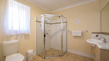 A bathroom with a glass-enclosed shower, a toilet, a sink, and a mirror.