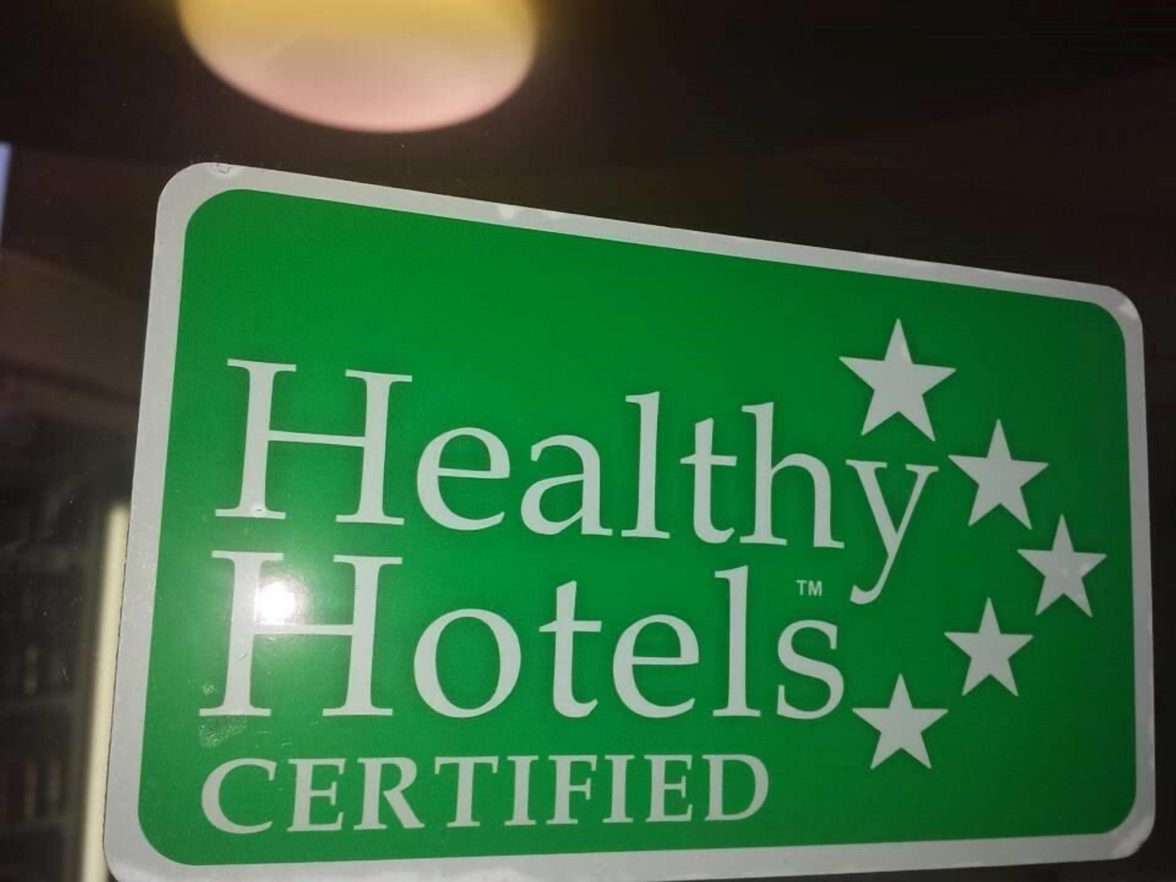 A green sign with the text "Healthy Hotels Certified" and five white stars.