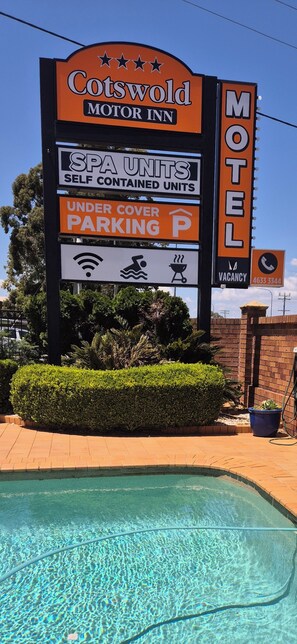 A motel sign with amenities including spa units, self-contained units, under cover parking, and a contact number.