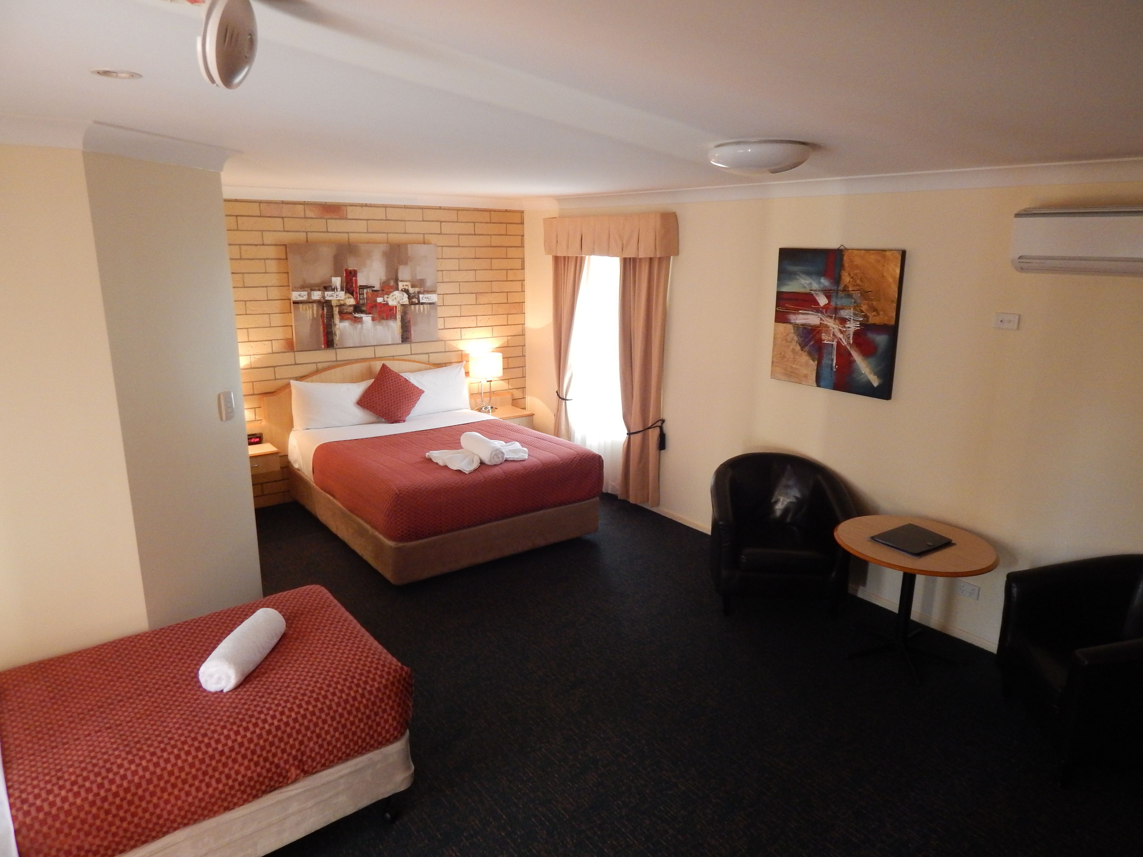 A hotel room with a bed, a small sofa, a desk, and a chair.