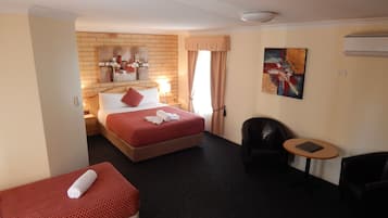 A hotel room with a bed, a small sofa, a desk, and a chair.