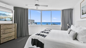 Une chambre d’hôtel moderne avec un grand lit, un bureau et une vue sur la mer.