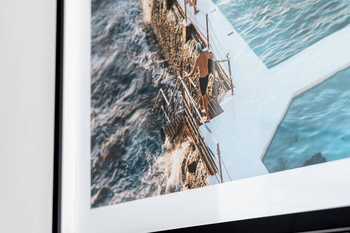 A framed photograph of a pier extending into the sea with people standing on it.