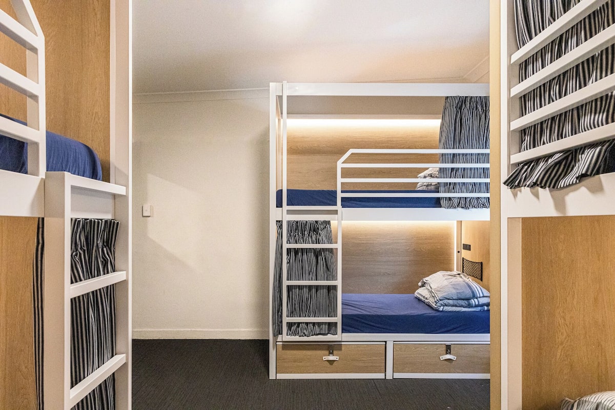 A bunk bed room with a wooden wardrobe and a built-in desk.