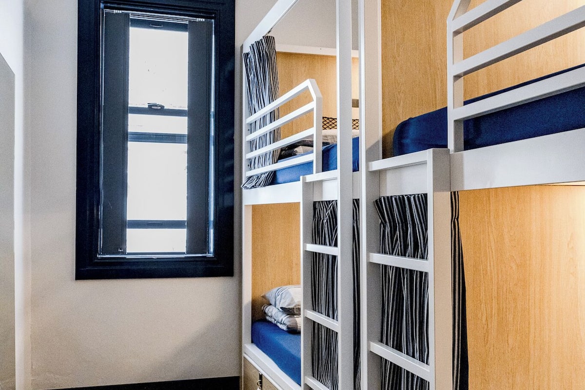 A bunk room with a window, bunk beds, and a carpeted floor.