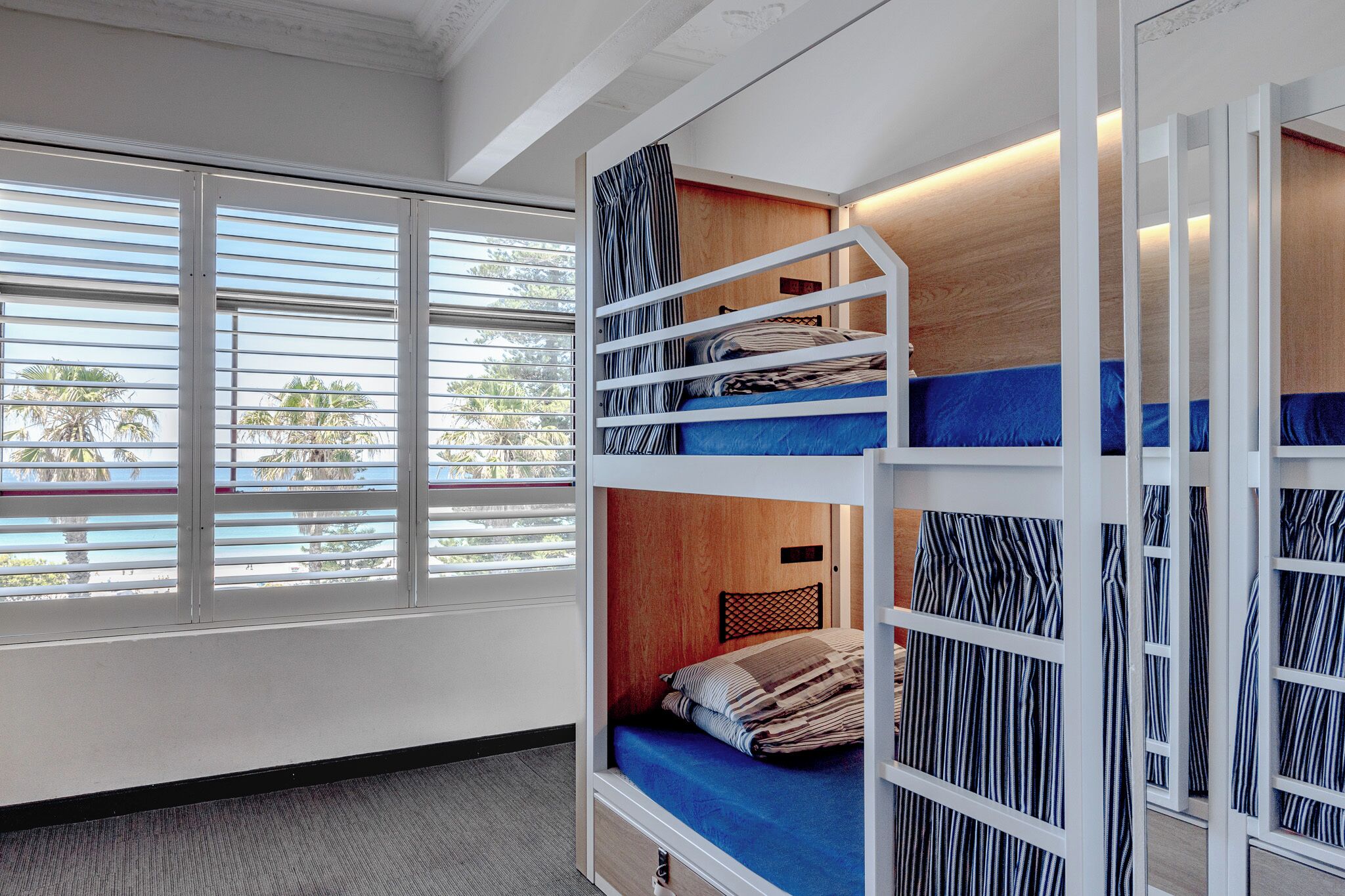 A bunk bed room with a large window, a wooden headboard, and a view of palm trees.