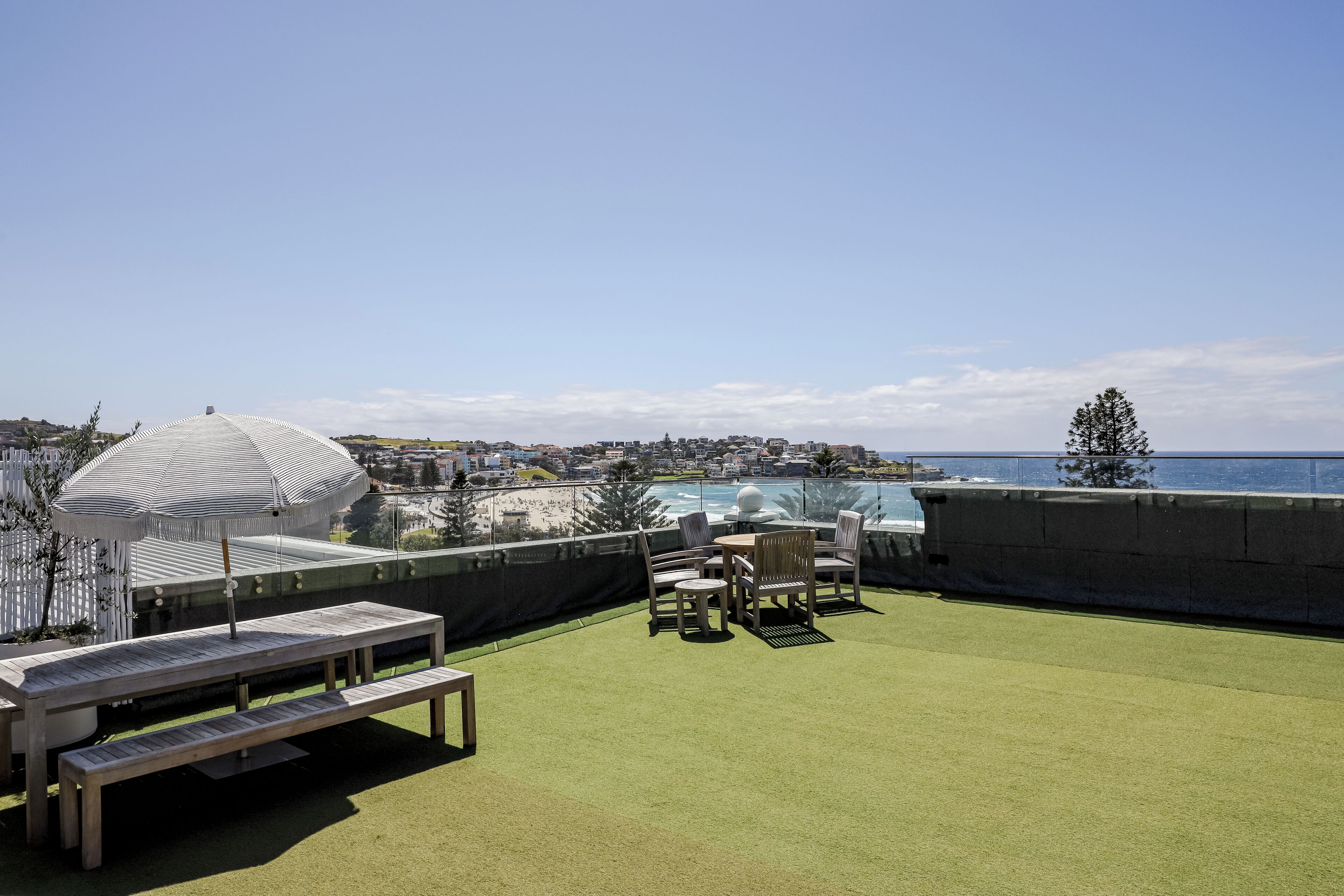 Une terrasse sur le toit offrant une vue sur la mer, un parasol blanc et du mobilier d’extérieur.