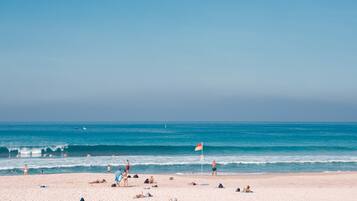 Perto da praia, areia branca, guarda-sóis, toalhas de praia