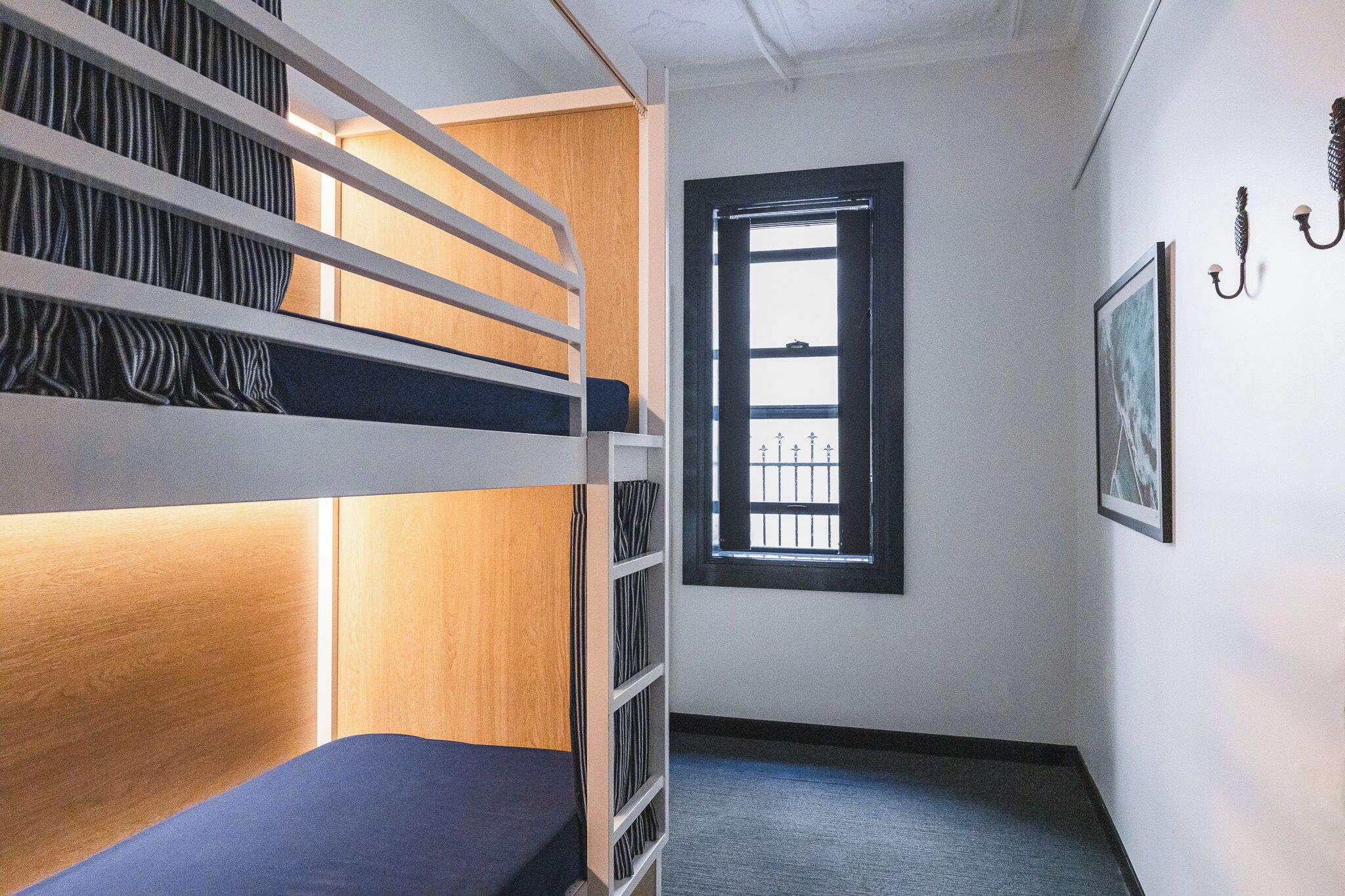 Une chambre avec un lit superposé, une fenêtre et un tableau au mur.