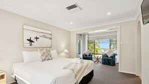 Una habitación de hotel moderna con una cama grande, vistas al exterior y un área de estar con una mesa y sillas.
