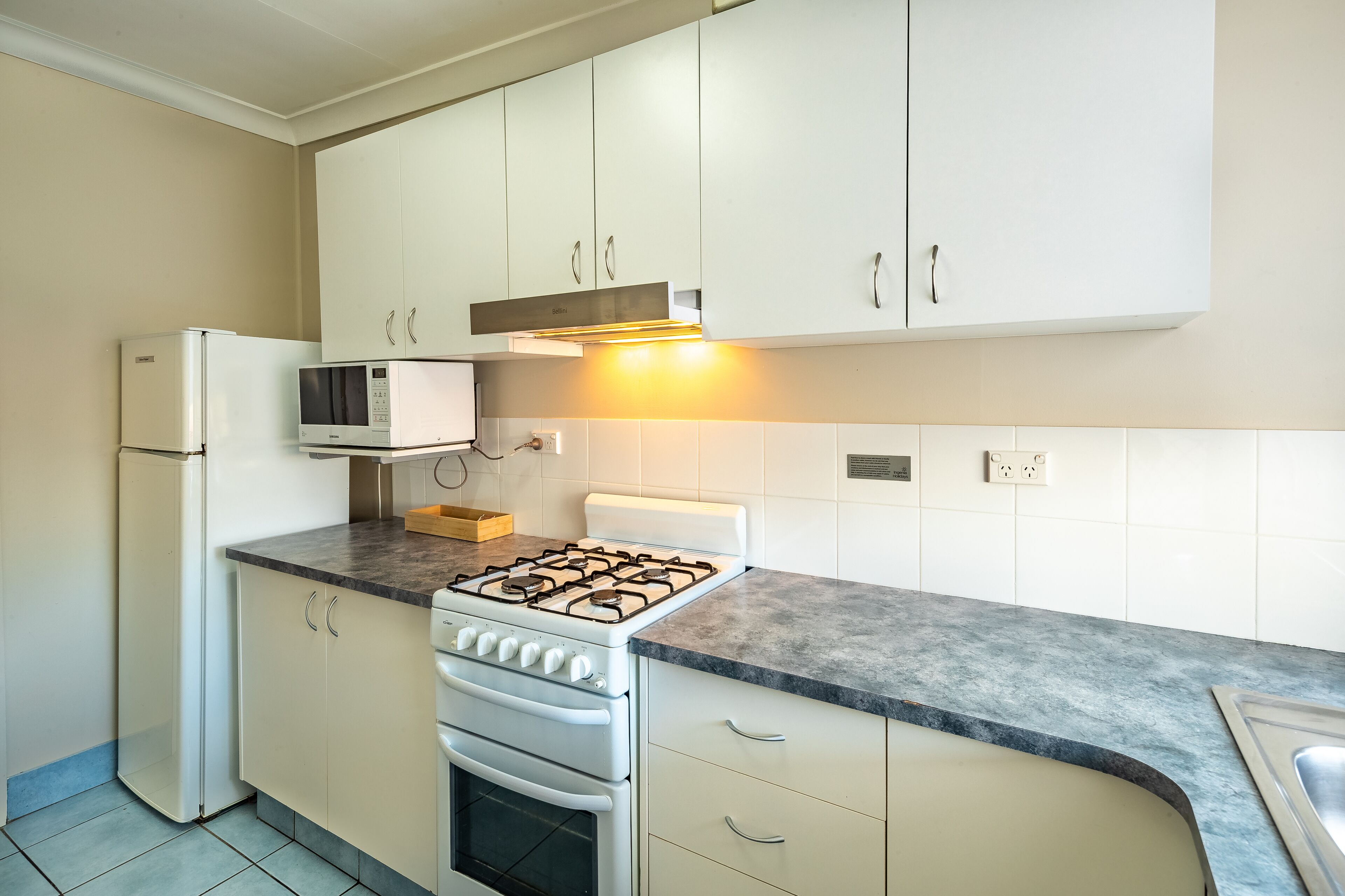 A kitchen with white cabinets, a gas stove, a microwave, and a refrigerator.