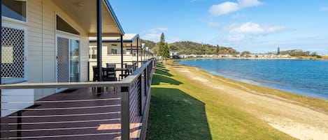 A row of cabins with a wooden deck and a view of a lake.