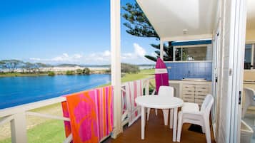 A covered outdoor area with a table and chairs, a view of the water, and a kitchen area with cabinets and a counter.
