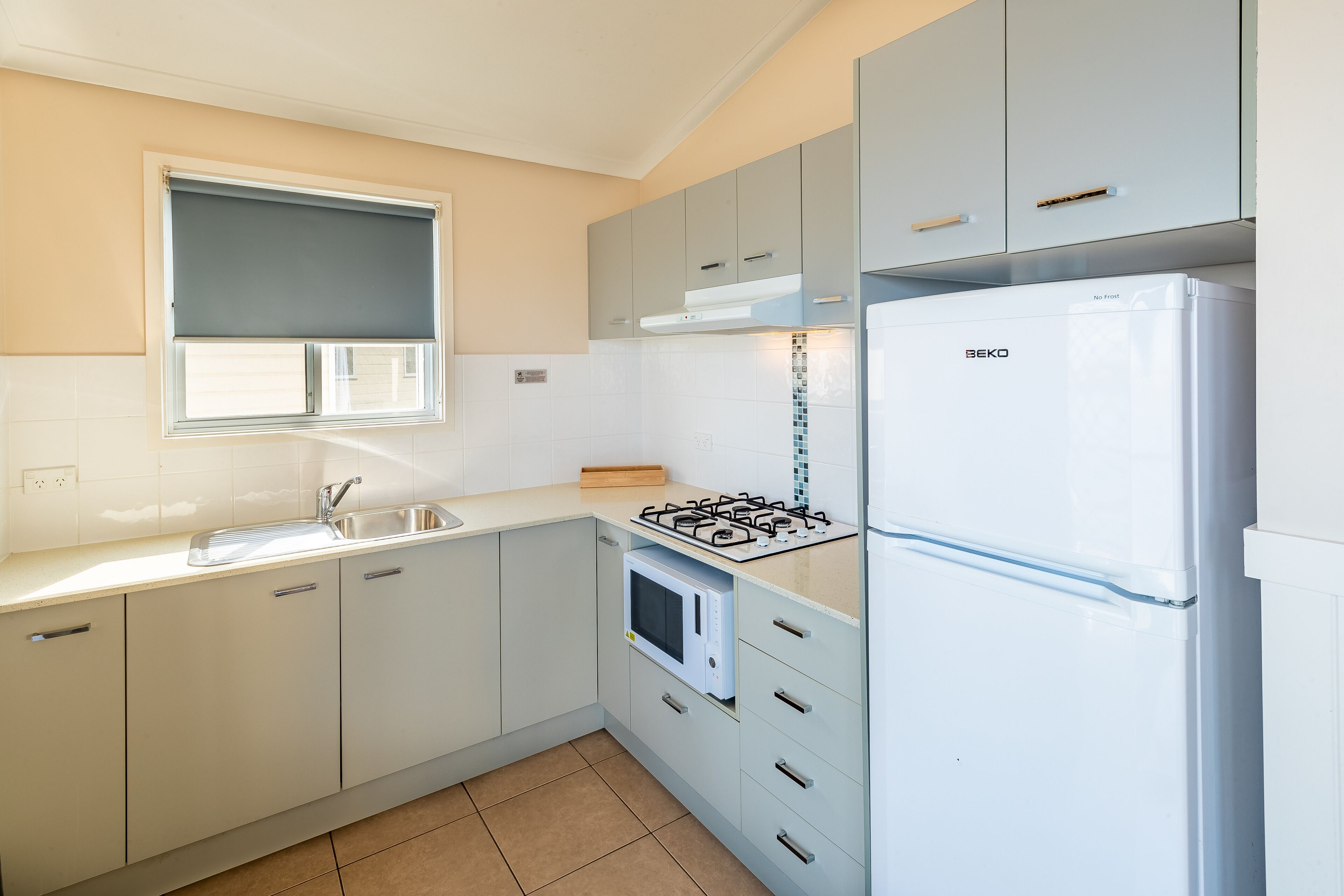 Une cuisine moderne équipée d’une cuisinière à gaz, d’un four à micro-ondes et d’un réfrigérateur blanc.