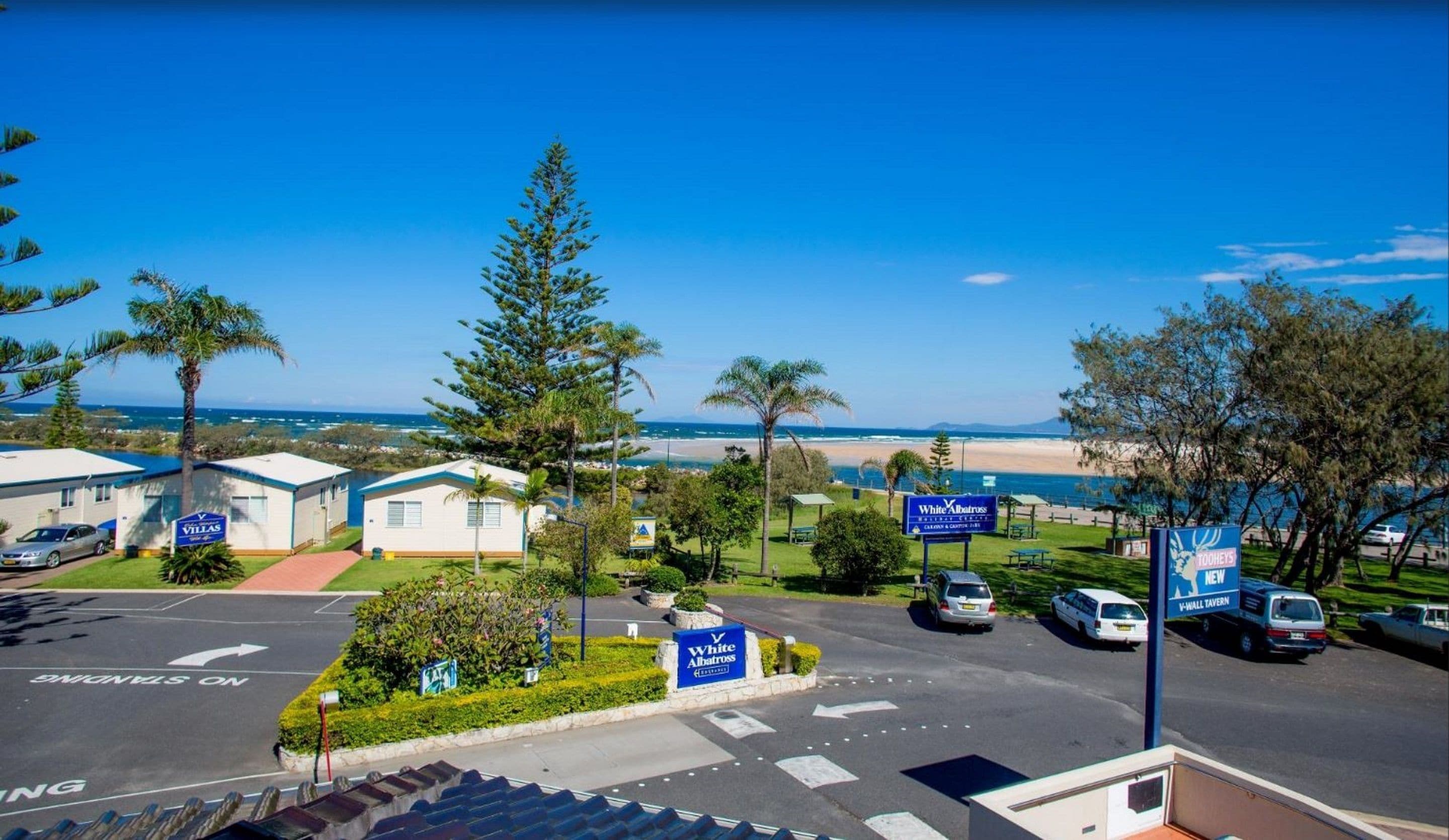 Un hotel frente al mar con villas, vistas a la playa y zona de estacionamiento.