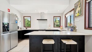 Una cocina moderna con una isla grande, electrodomésticos de acero inoxidable y taburetes negros.