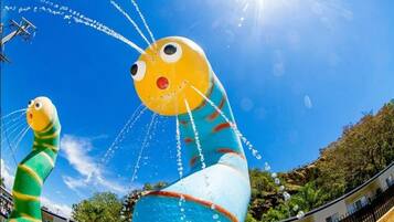Una gran escultura inflable de una criatura amarilla con nariz roja y cuerpo azul, frente a un cielo azul despejado.
