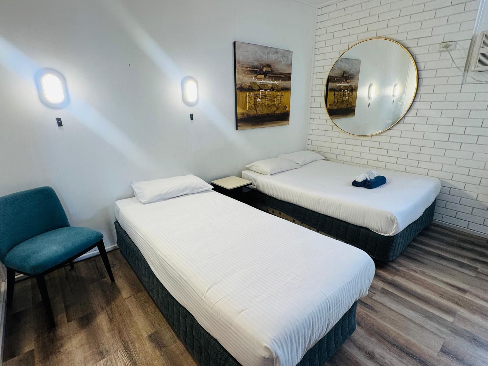 Una habitación con dos camas, una silla y un espejo montado en la pared.