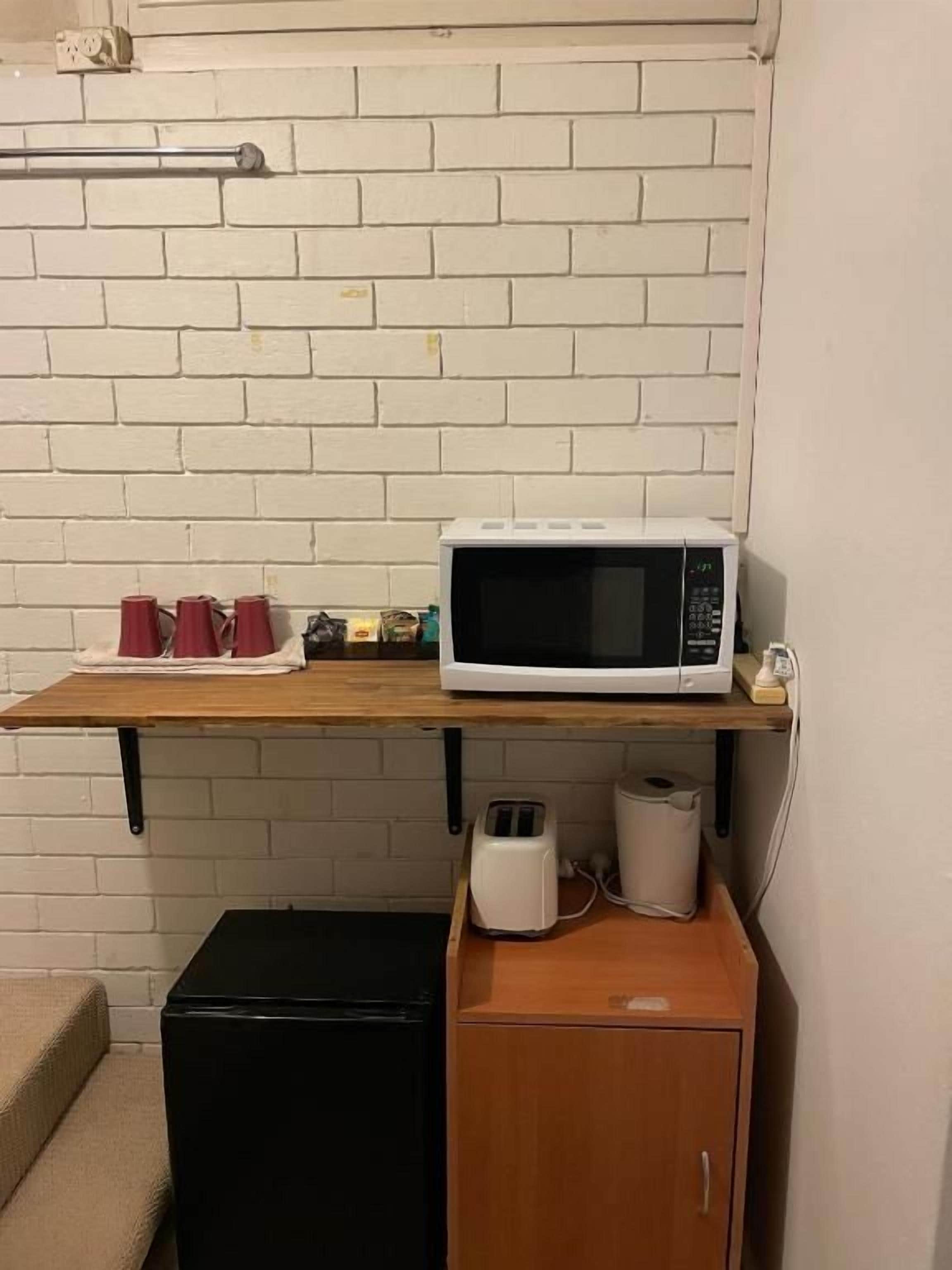Una kitchenette equipada con microondas, tostadora y un refrigerador pequeño.