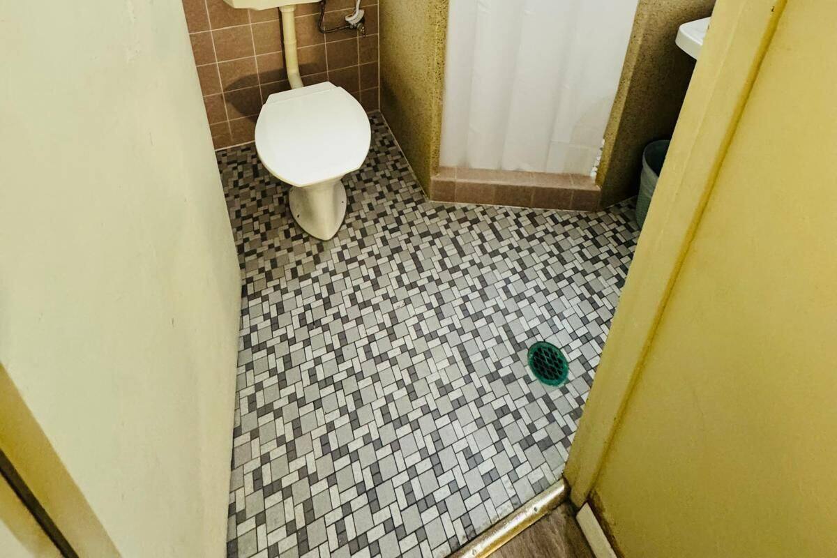 A small bathroom with a toilet, a shower curtain, and a tiled floor.