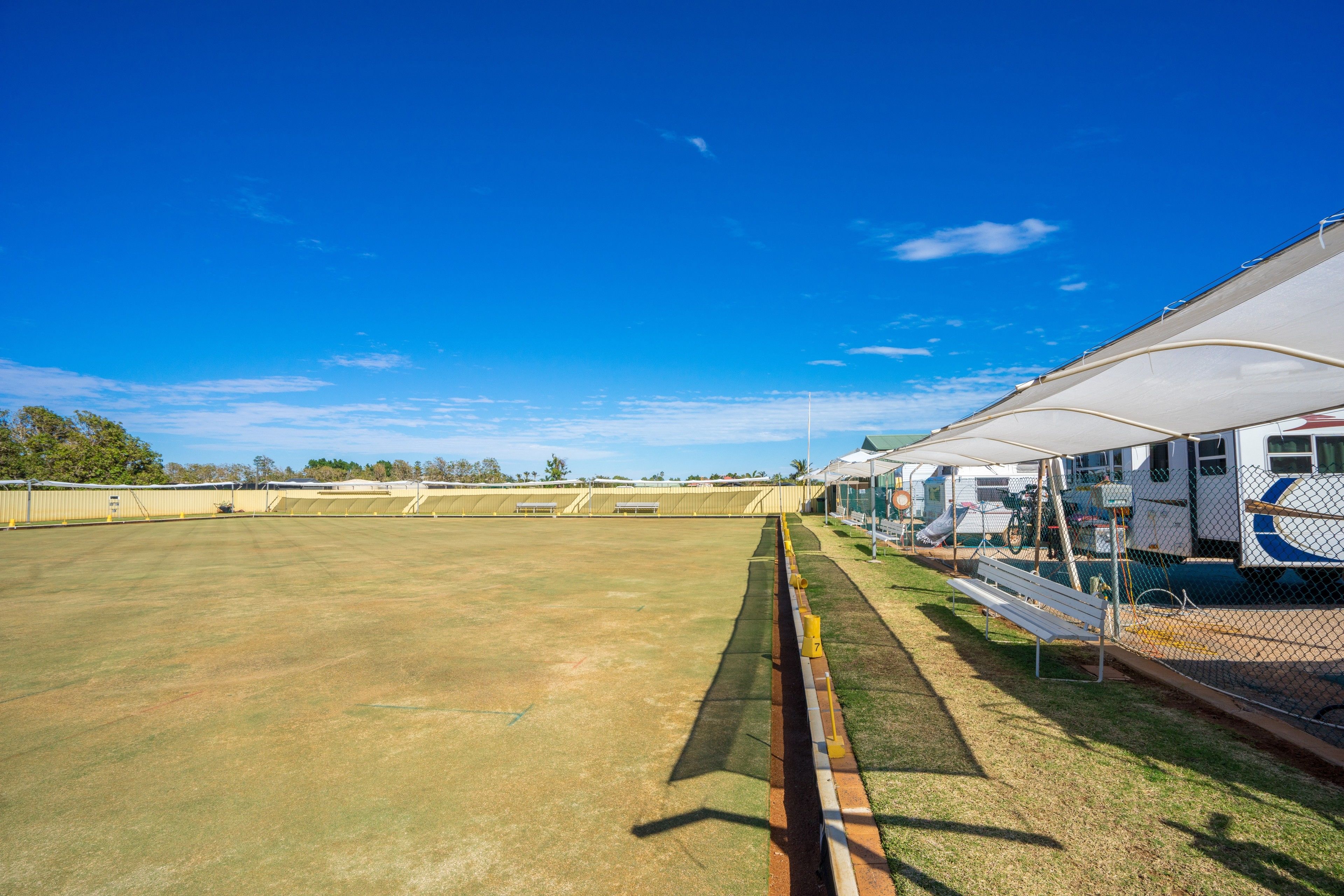 A large, open, grassy field with a white canopy structure on the right, likely for shade or shelter.