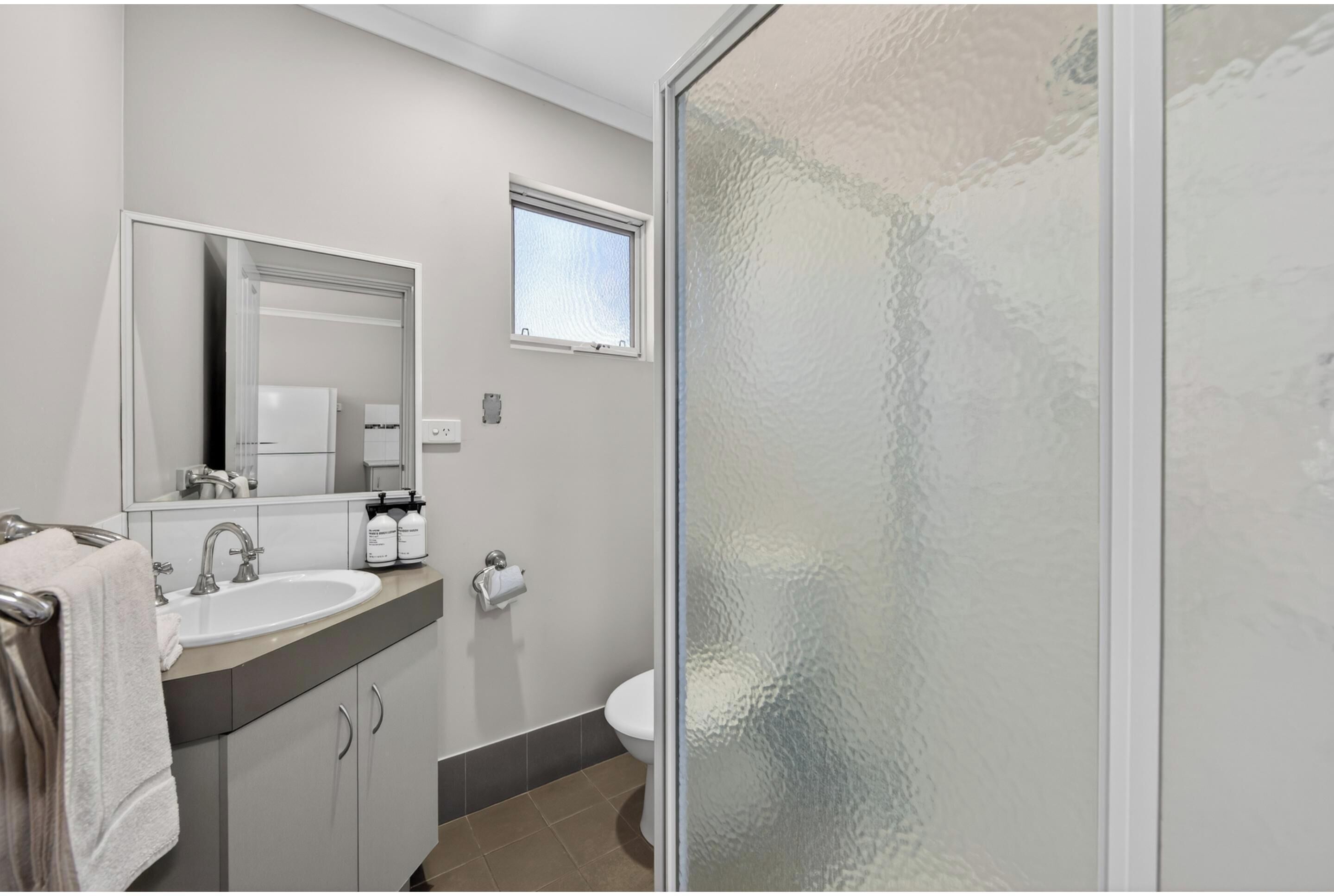 A modern bathroom with a sink, mirror, and toilet.