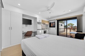A modern hotel room with a large bed, a desk, kitchenette, and a balcony with a view. - Discovery Parks - Carnarvon (Kingsford)