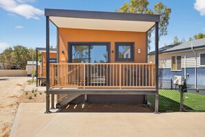 A modern building with a covered balcony, a staircase leading to the entrance, and a fenced yard. - Discovery Parks - Carnarvon (Kingsford)