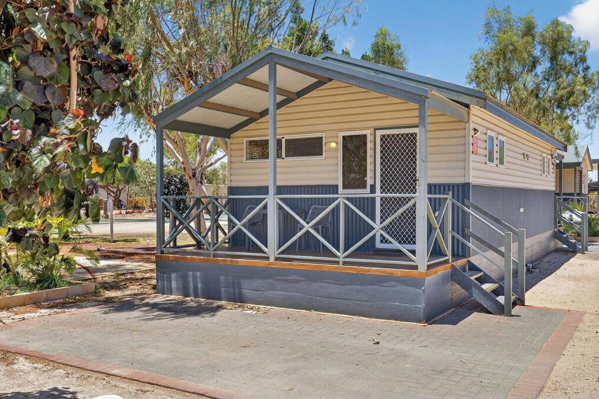 A small, single-story mobile home with a covered porch and a staircase leading to the entrance.