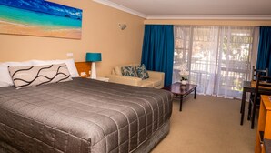 A hotel room with a large bed, a sofa, a small table, and a chair.