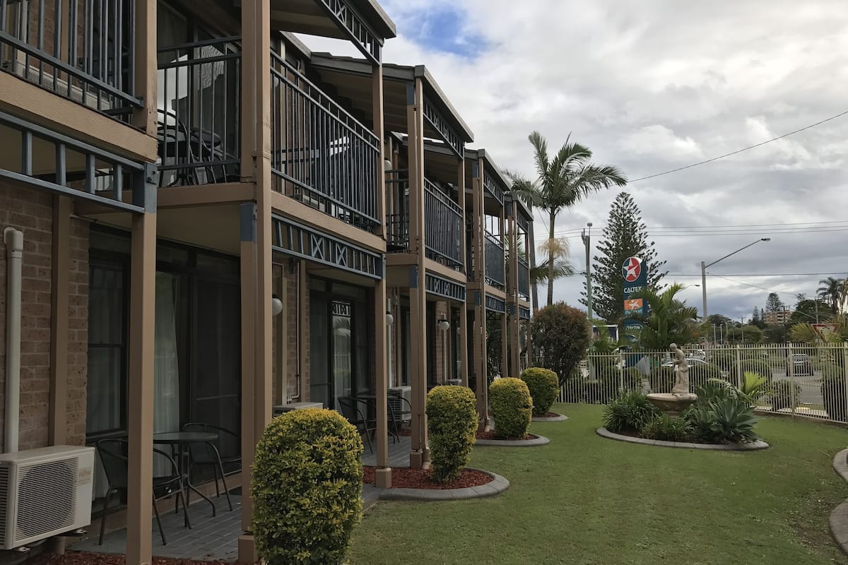 A multi-story hotel with balconies, outdoor seating, and well-maintained landscaping.