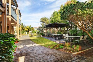 A courtyard with outdoor seating, a covered area, and a brick pathway.