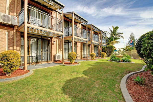 A multi-story hotel with balconies, outdoor seating, and well-maintained landscaping.