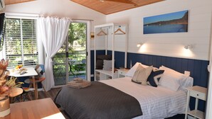 A bedroom with a bed, bedside tables, a desk with a chair, and a window with curtains.