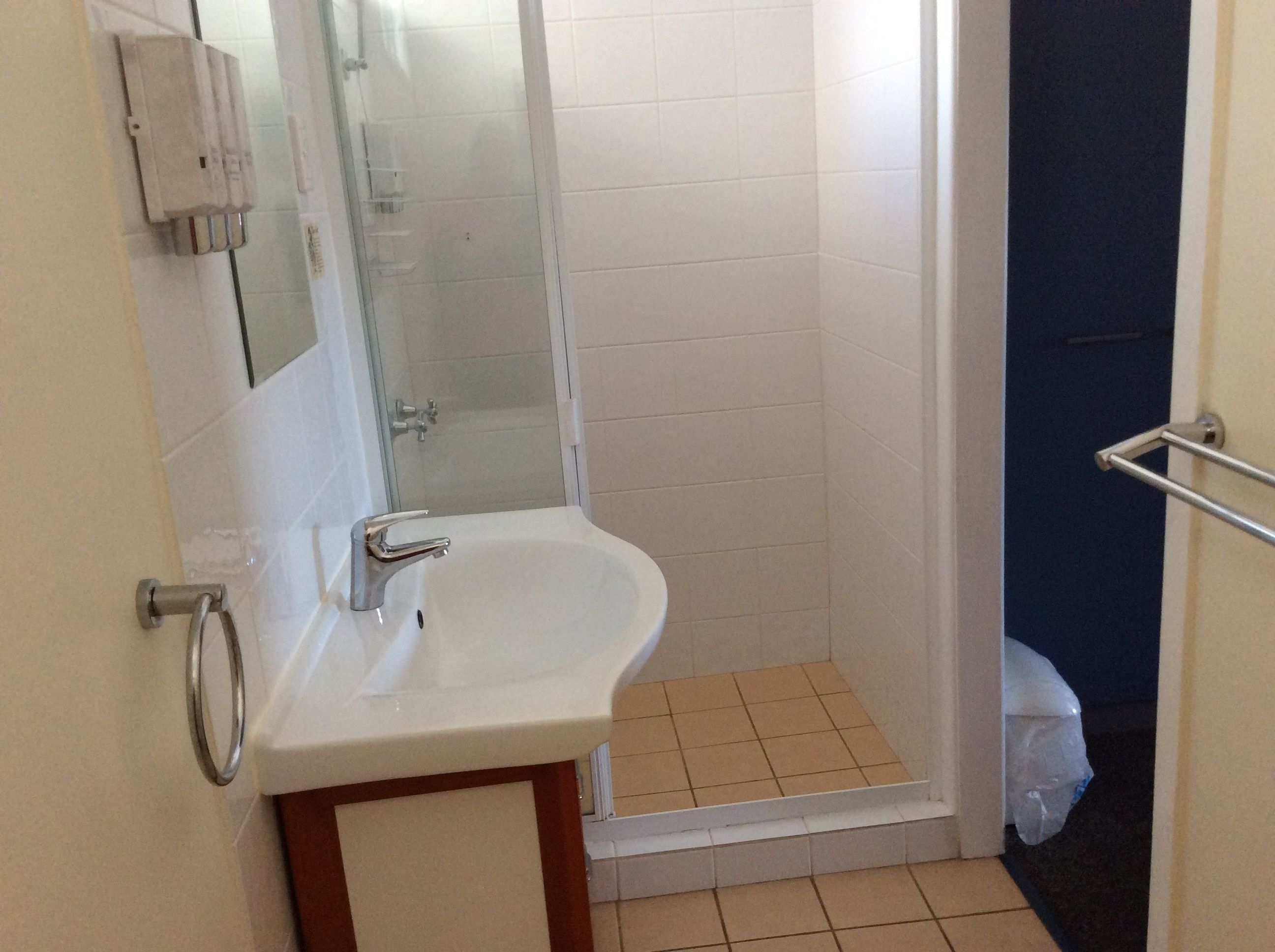 A bathroom with a white sink, a glass shower enclosure, and a blue door.