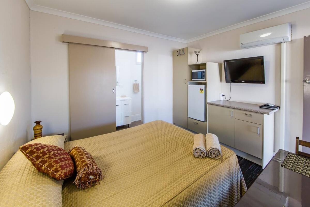 Ein Hotelzimmer mit einem Bett, einem Schreibtisch, einem Fernseher und einer Tür mit der Nummer 12.