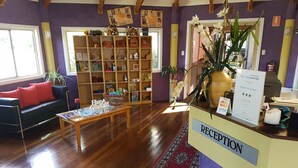 A reception area with a reception desk, a sofa, a coffee table, and a bookshelf filled with books and decorative items. - Kingaroy Country Motel (Kingaroy)