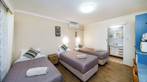 A hotel room with three beds, a bathroom, and a kitchenette. - Kingaroy Country Motel (Kingaroy)