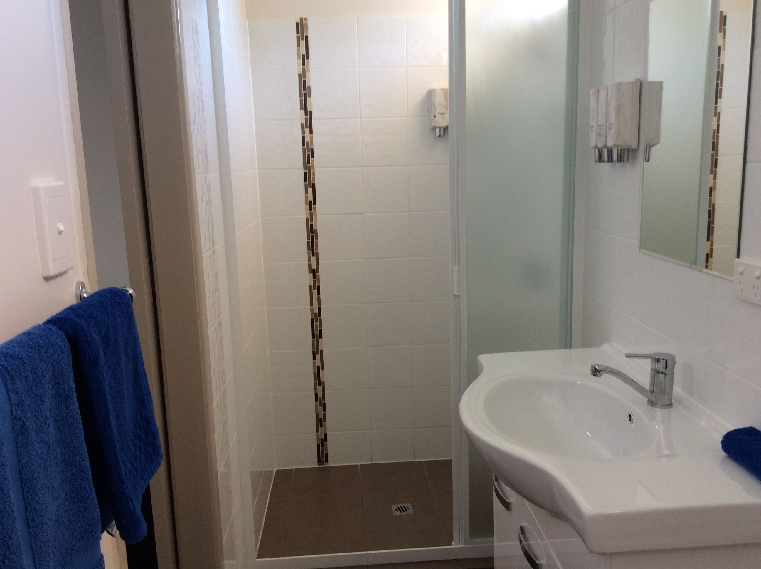 A bathroom with a shower, a sink, and a towel rack.