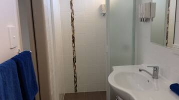 A bathroom with a shower, a sink, and a towel rack.