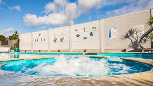 A swimming pool with water jets, a tiled deck, and a wall with decorative tiles and a pool safety sign. - Kingaroy Country Motel (Kingaroy)