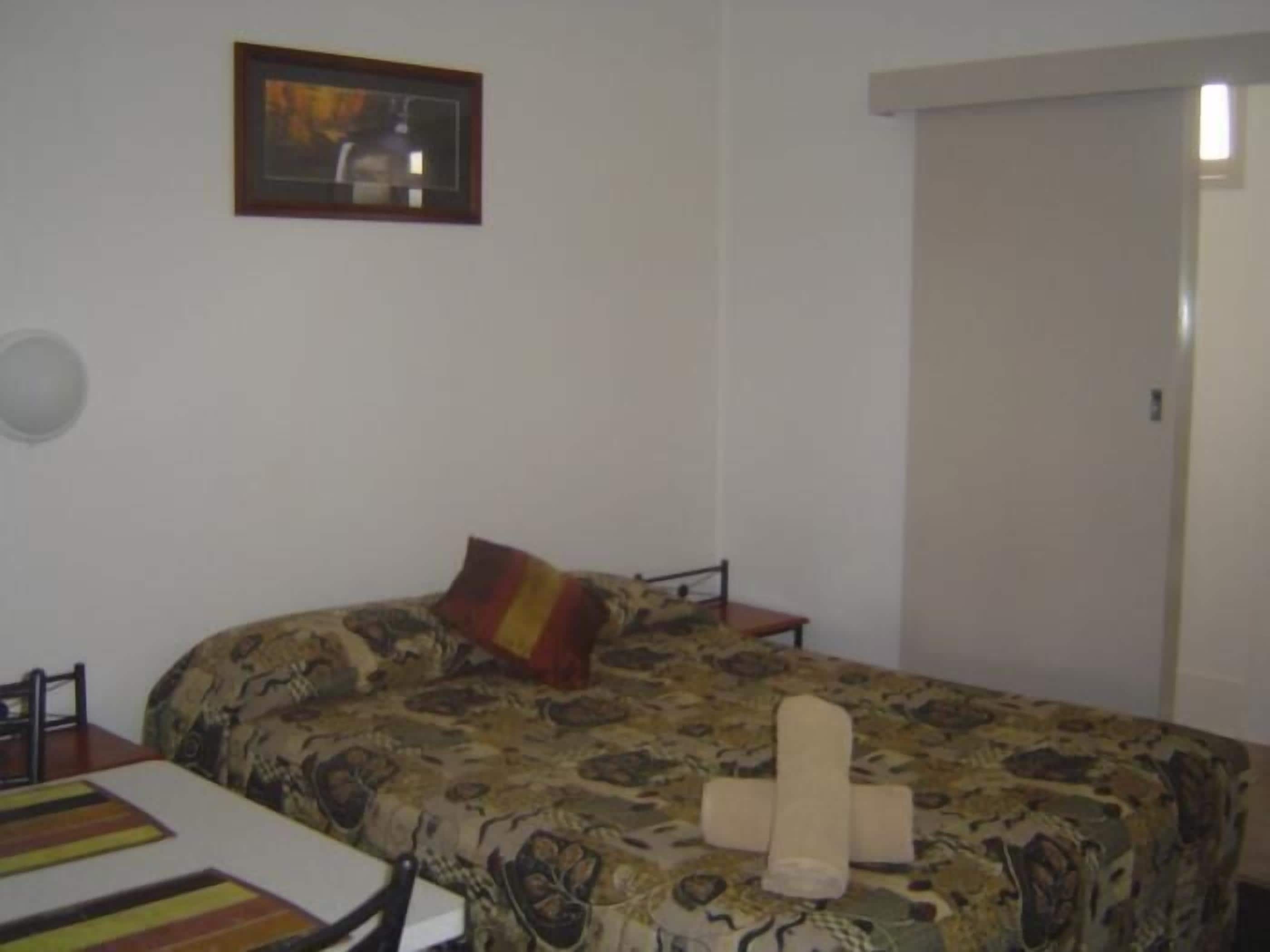 A room with a bed, a chair, a table, and a door.